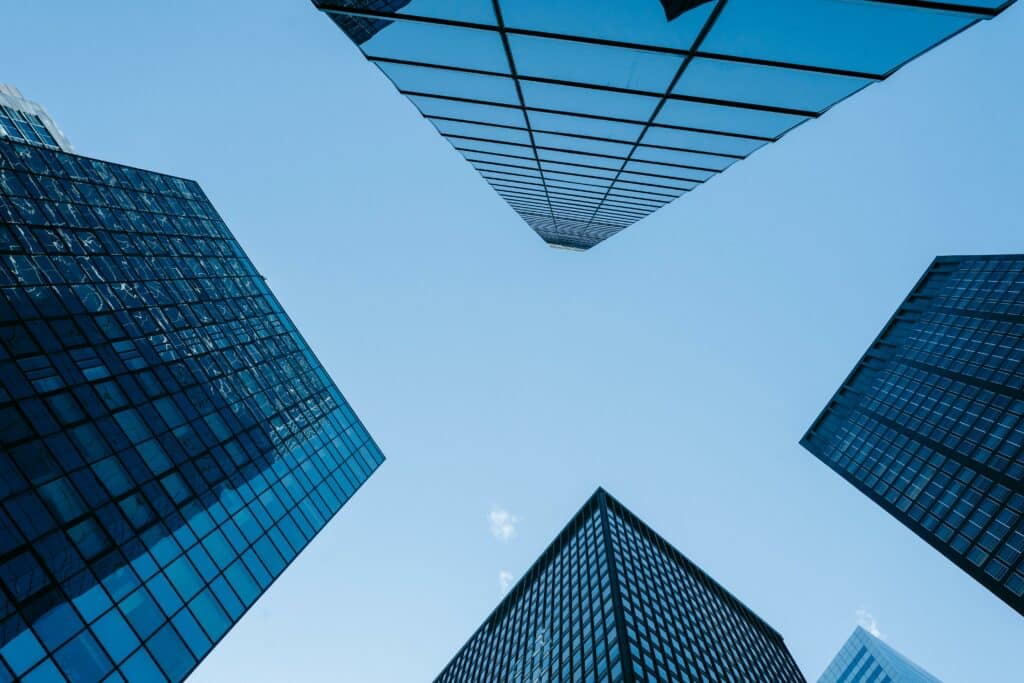 Upward view of modern glass office buildings, representing commercial environments where Crimsafe security screens provide discreet, high-strength protection without compromising architectural design.