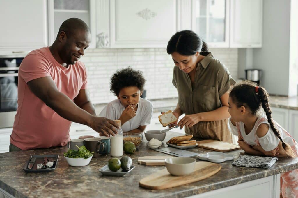 Family preparing food together in a bright, modern kitchen, reflecting the peace of mind and everyday safety supported by Crimsafe security screens in their Carrara home.