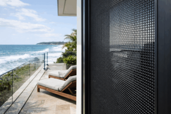 Marine-grade security screen installed on a coastal home, designed to resist salt air and harsh weather conditions.